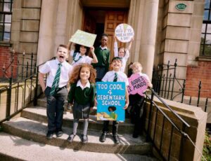 A group of school children holding banners outside a school