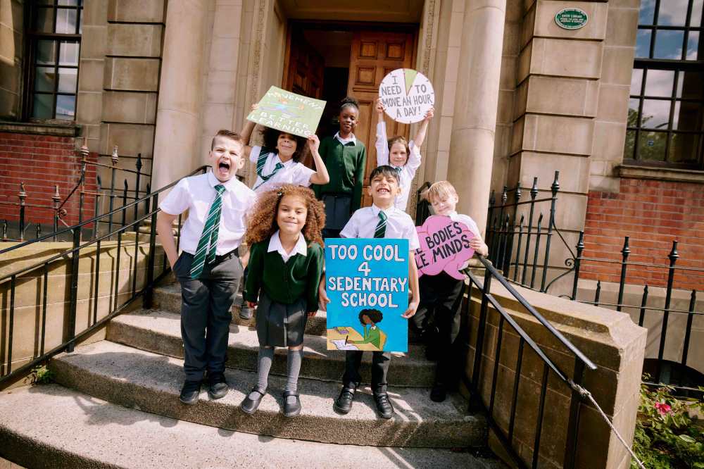 A group of school children holding banners outside a school