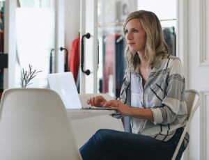 A woman sat at a desk working on a laptop representing The Digital Markets, Competition and Consumers Act 2024