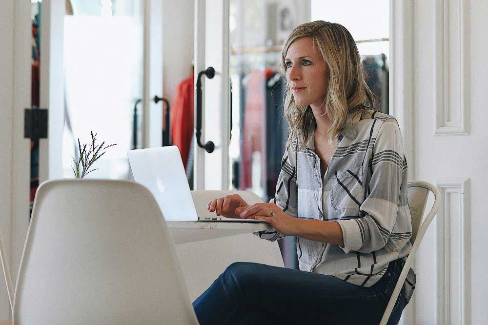 A woman sat at a desk working on a laptop representing The Digital Markets, Competition and Consumers Act 2024