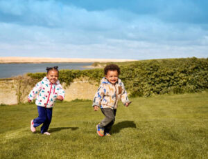 A young boy and girl running across a grass banking