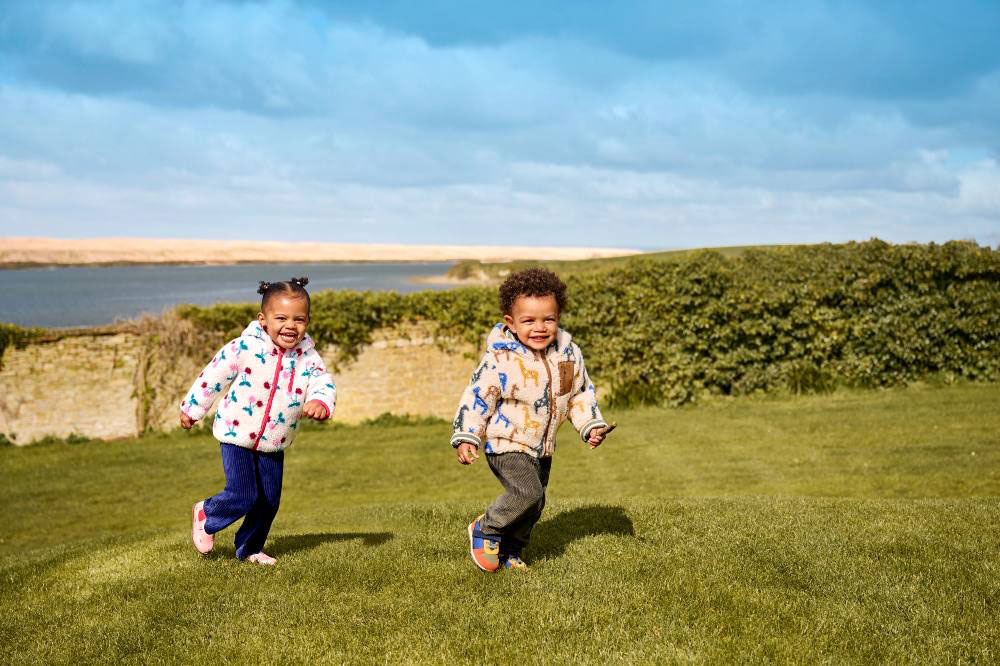 A young boy and girl running across a grass banking