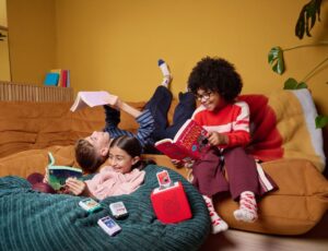 Children lying on a sofa laughing and using Book Pocket Tonies