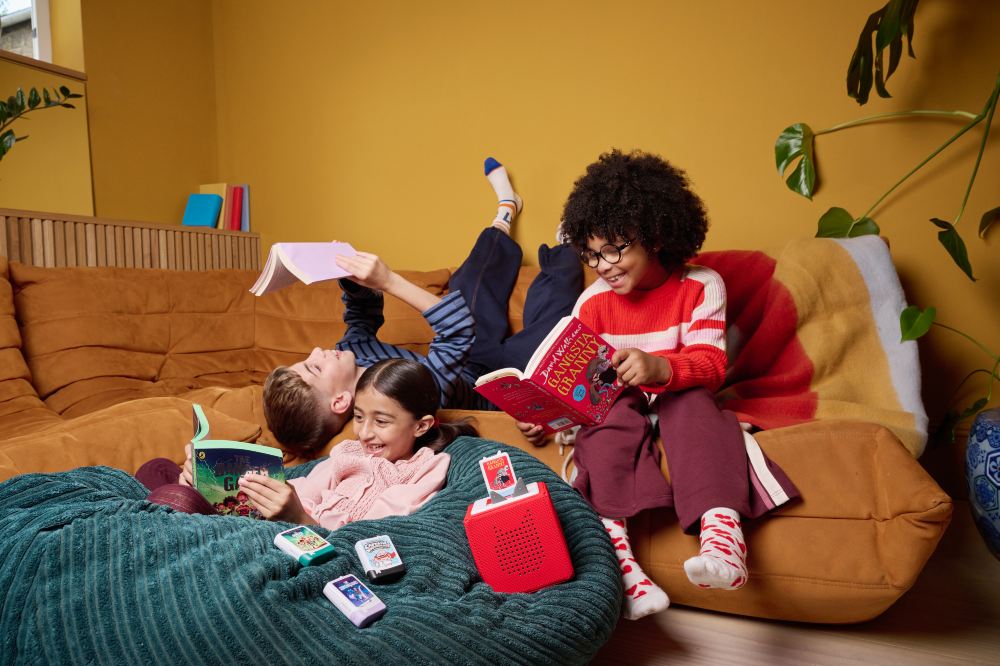 Children lying on a sofa laughing and using Book Pocket Tonies