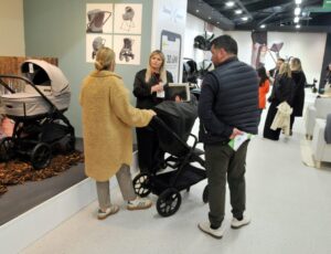 People stood in an aisle of Harrogate International Nursery Fair looking at a pram