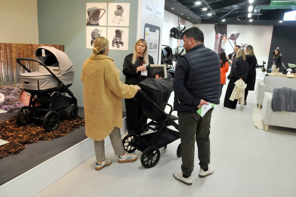 People stood in an aisle of Harrogate International Nursery Fair looking at a pram