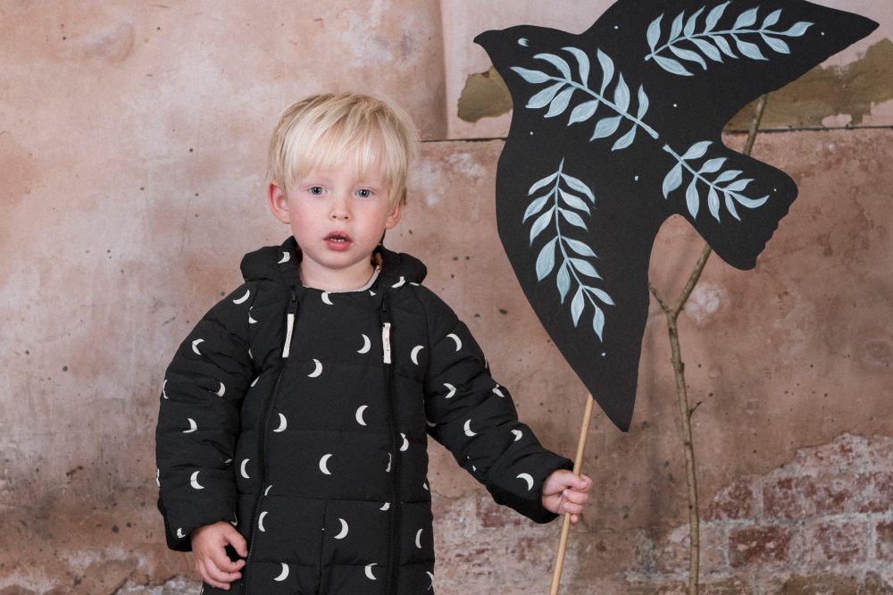 A young boy wearing a moon print onesie by Organic Zoo x Toastie