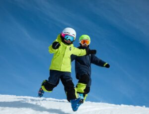 Two children running down a snow slope wearing skiwear from the new PO.P On Adventure Ski Edition collection