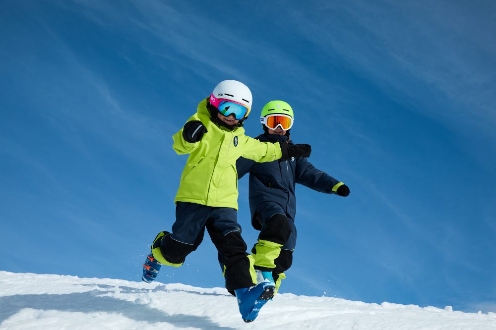 Two children running down a snow slope wearing skiwear from the new PO.P On Adventure Ski Edition collection