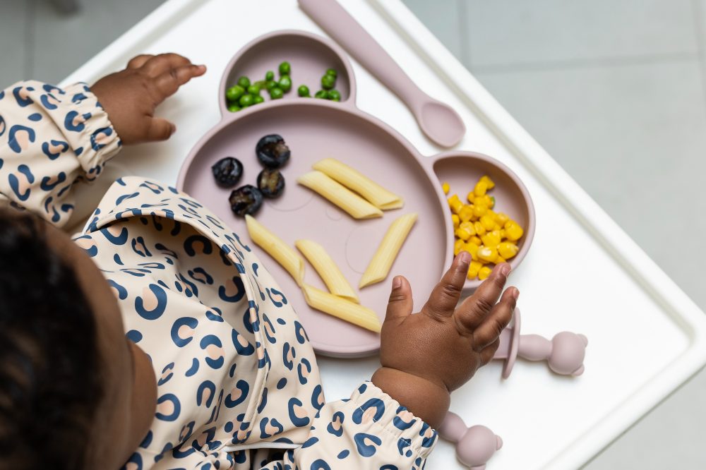 A baby in a high chair wearing a pink leopard print bib by Chomp, a winner of #SBS Small Business Sunday