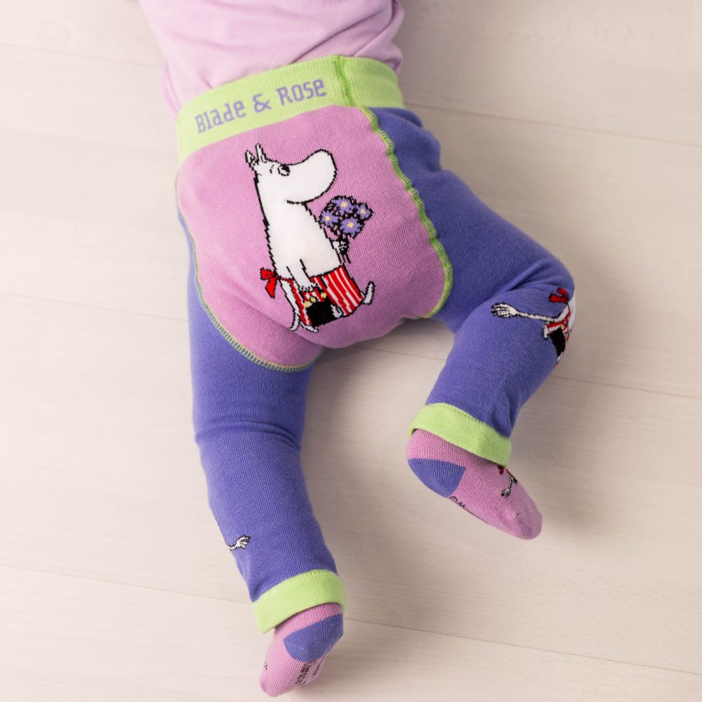 A child crawling on the fllor wearing leggings with a Moomin character on the bottom 