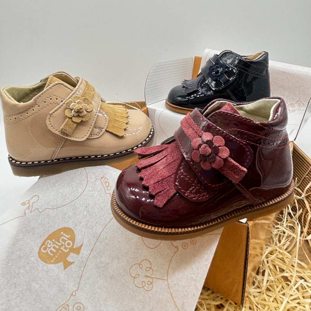 Three patent toddler shoes displayed on a shoe box