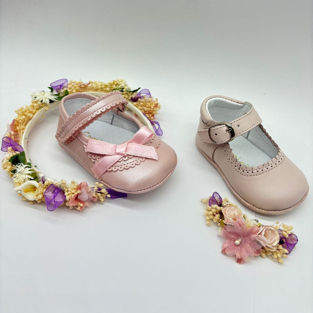 Two children's pink shoes displayed with flowers