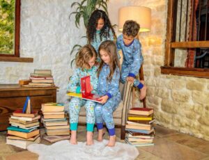 A group of children surrounded by piles of books and wearing pyjamas from the new Ducky Zebra x Roald Dahl collection