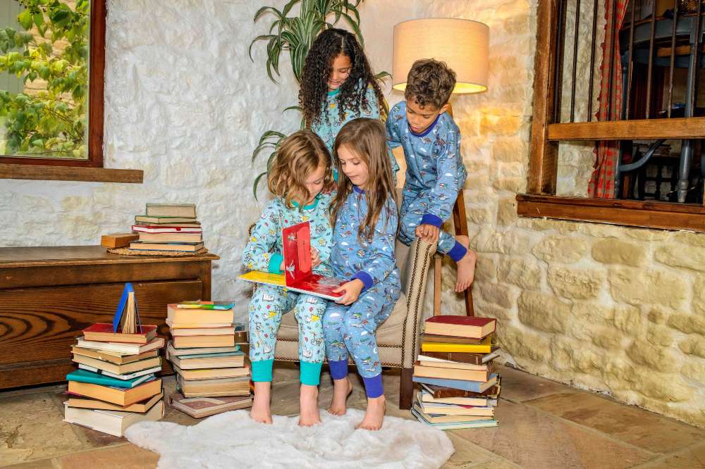 A group of children surrounded by piles of books and wearing pyjamas from the new Ducky Zebra x Roald Dahl collection