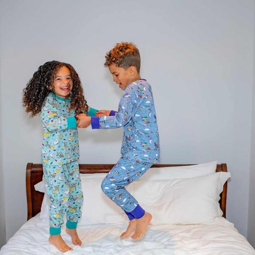 Two children jumping on a bed wearing pyjamas from the Ducky Zebra x Roald Dahl collection