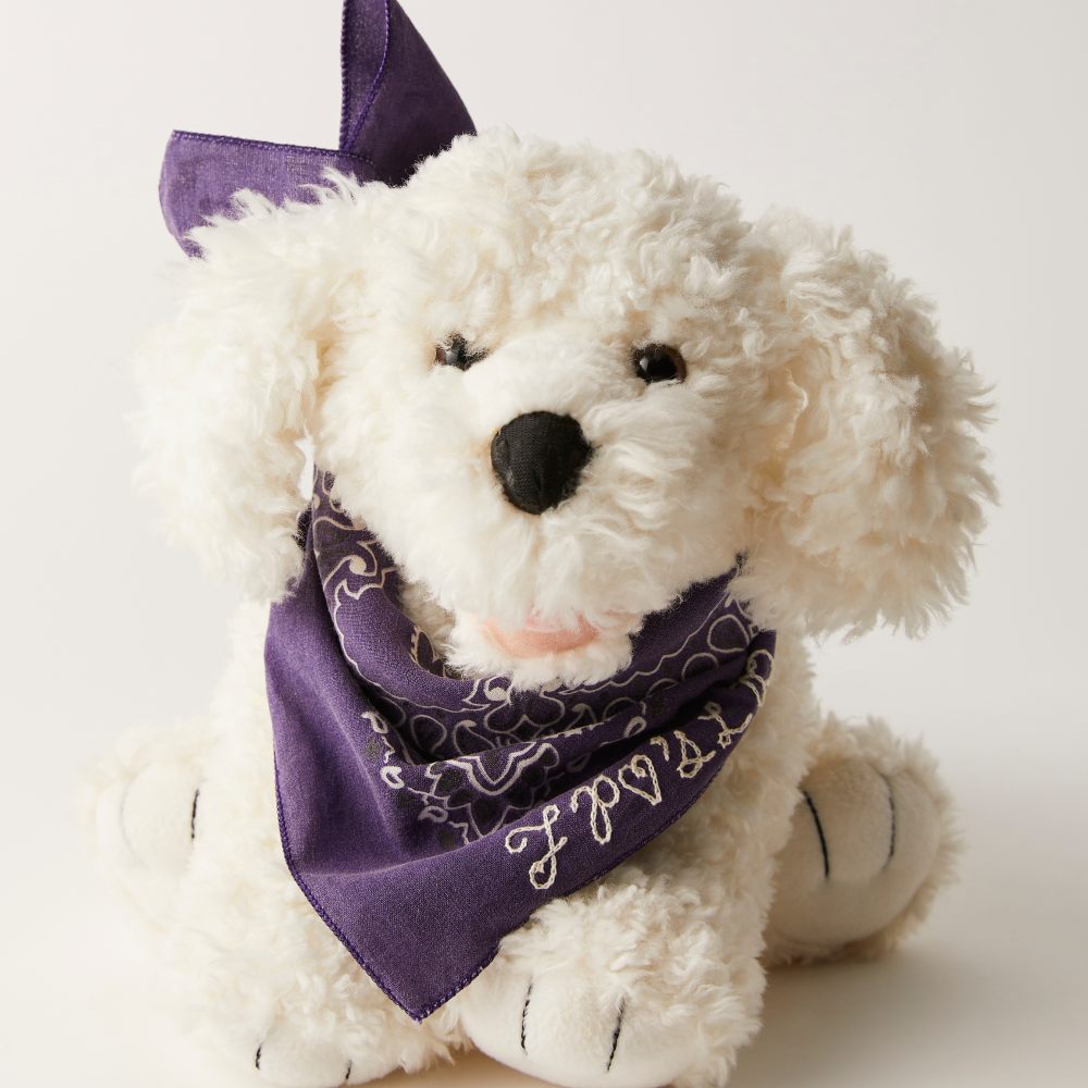 A white toy dog wearing a blue bandana from the Loved Before x Free People collaboration