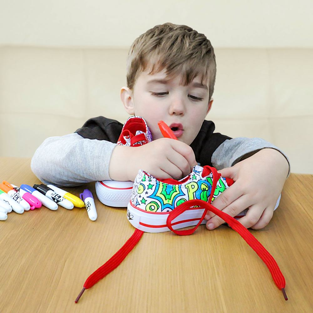 A young boy sat at a table colouring in a shoe 