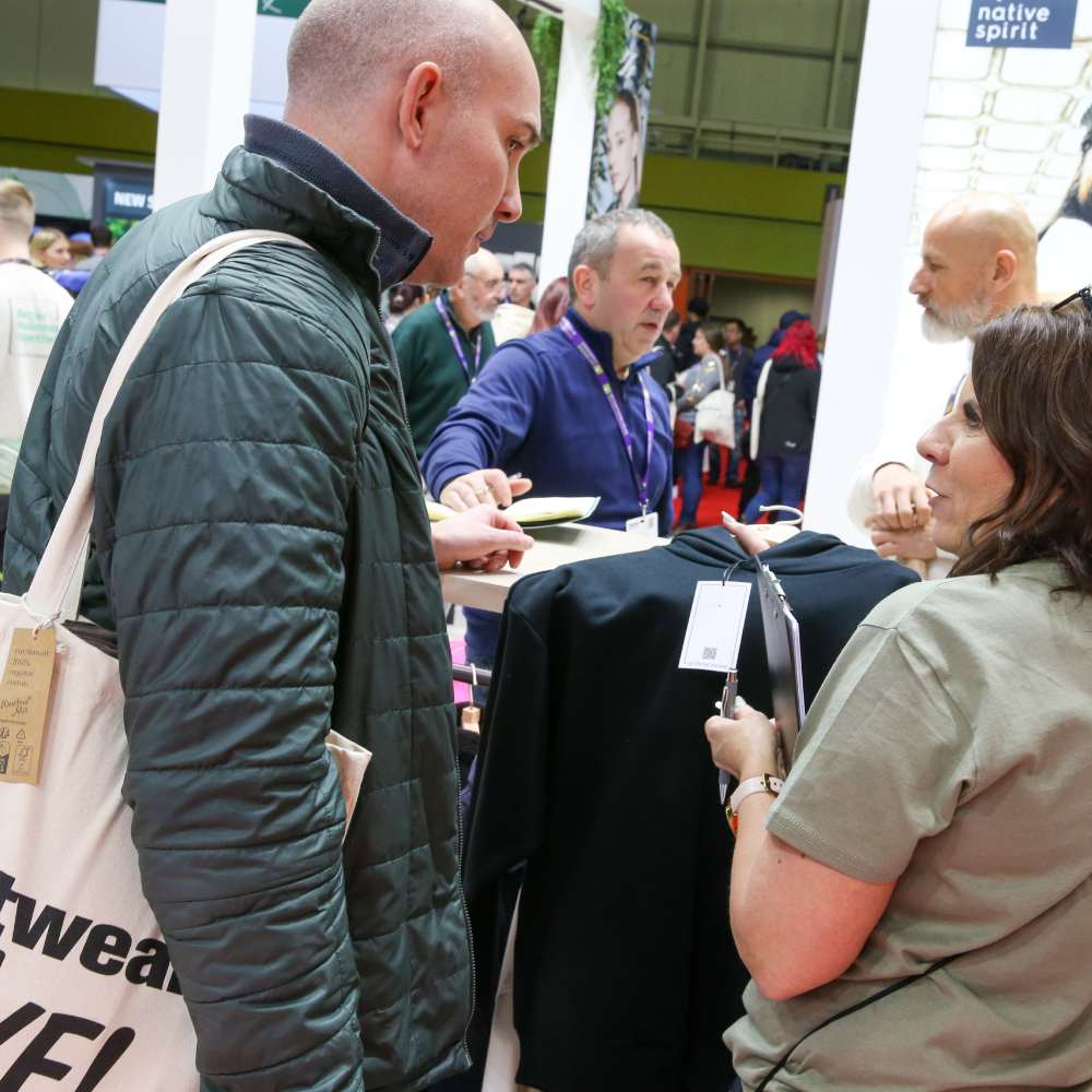 People stood on a stand looking at a garment at Printwear & Promotion LIVE!