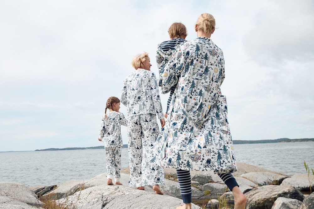 A woman carrying a young boy walking with another woman and young girl next to the sea