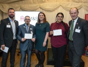 A group of people stood on a stage in front of an M&S sign for the Marks & Start campaign