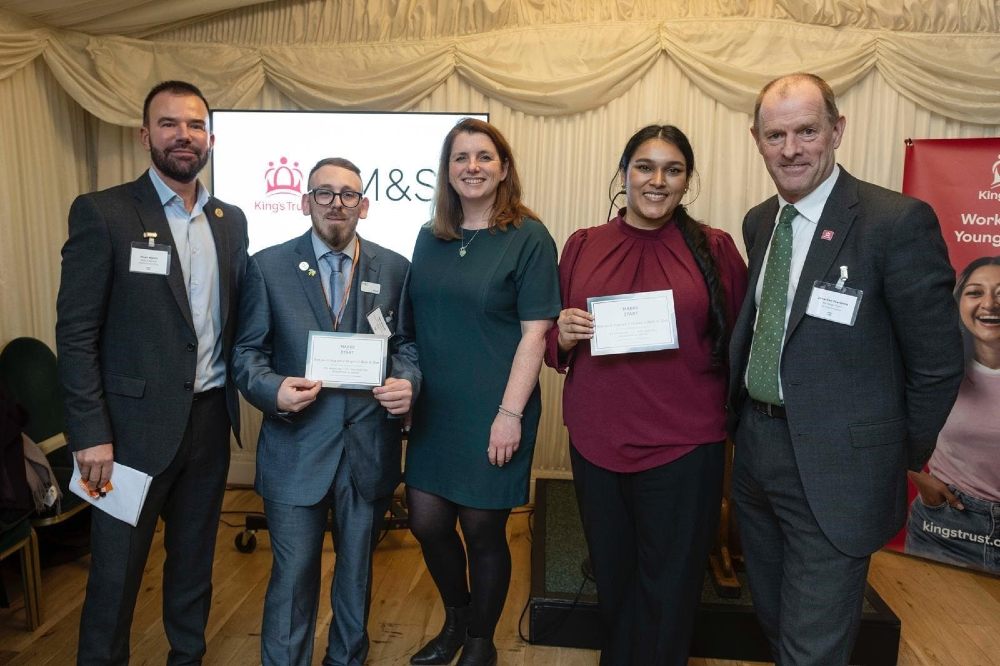 A group of people stood on a stage in front of an M&S sign for the Marks & Start campaign