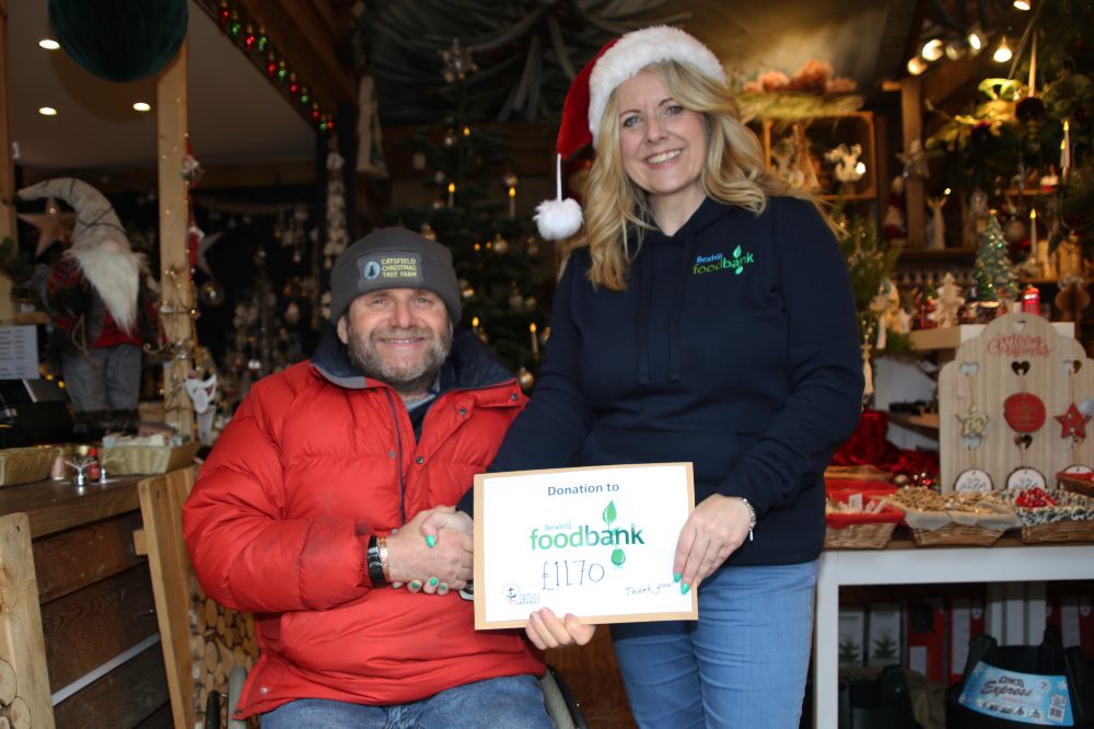 A man shaking a woman's hand who is holding a certificate on a Christmas stand on Small Business Saturday