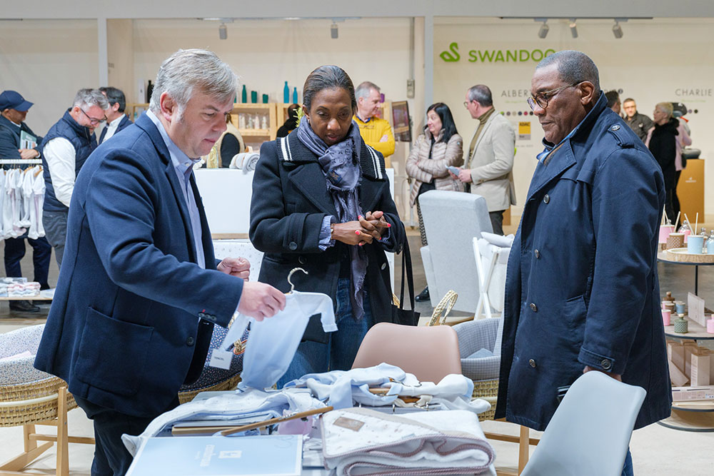 Buyers stood at a stand looking at clothing samples at BKS + FIMI