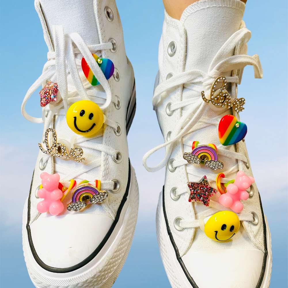 A pair of white trainers with different charms attached to the laces 