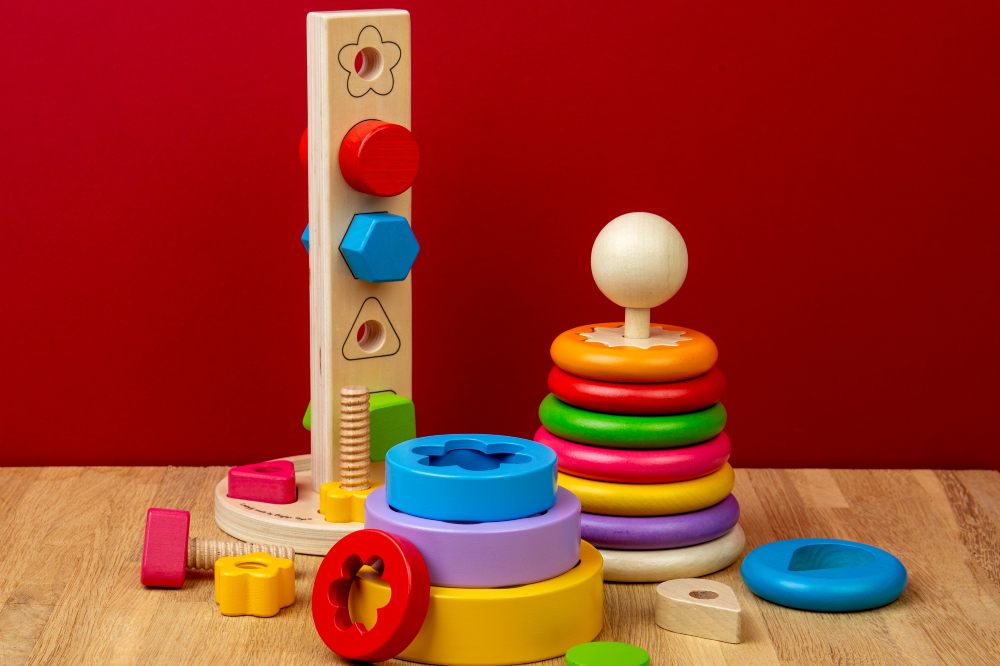 The new Montessori toy range by Bigjigs Toys displayed on a wooden table against a red background