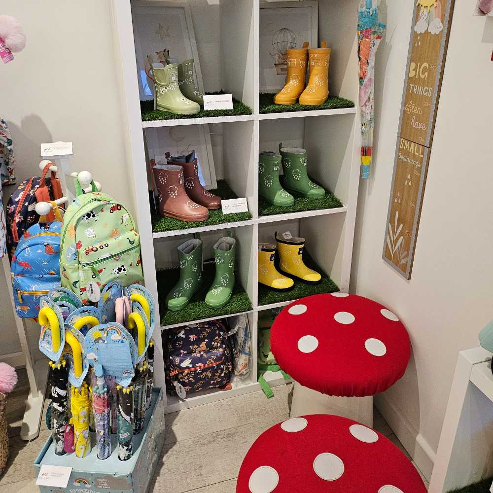 Children's wellies and umbrellas on display beside toadstool chairs in the Hettie & Sid store 