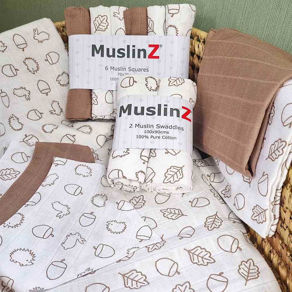 Cot sheets and muslins with an acorn print displayed in a basket 