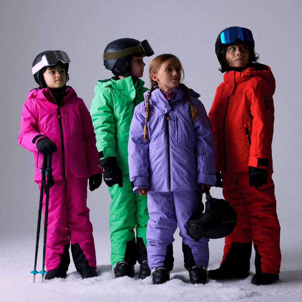 Four children stood in a line wearing brightly coloured skiwear 