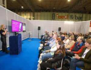 A speaker stood in front of an audience at Printwear & Promotion LIVE!