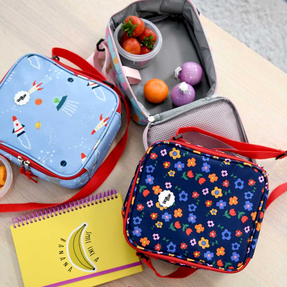 Children's lunch bags displayed on a table beside a yellow notebook 