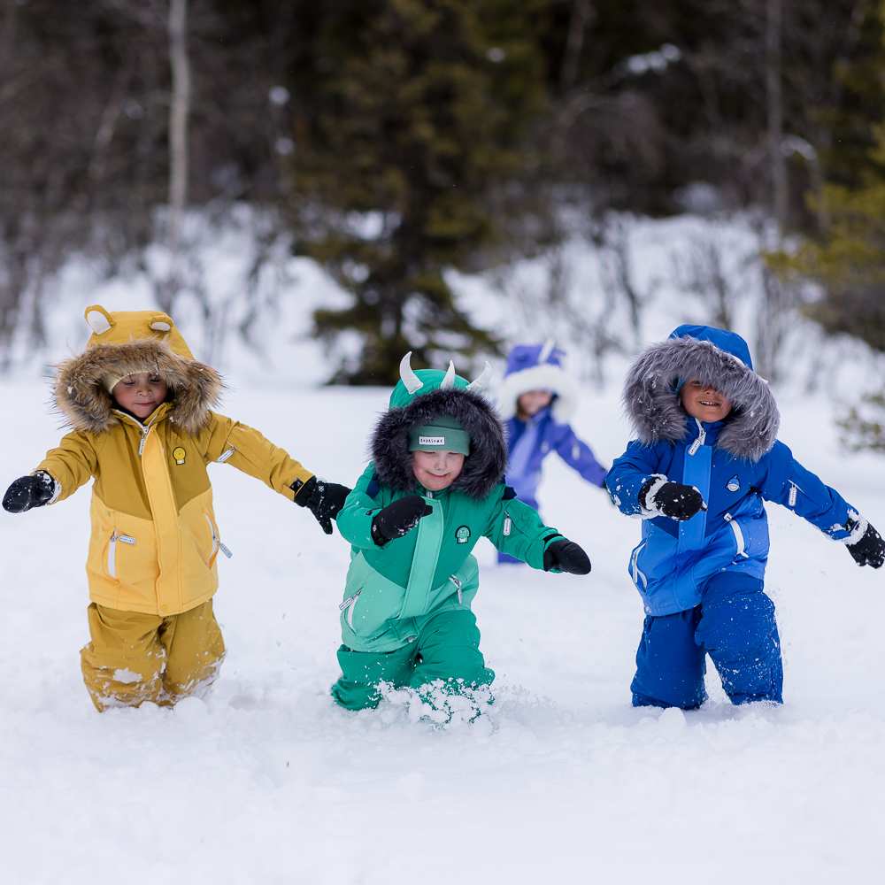 Three children walking through snow in skiwear 