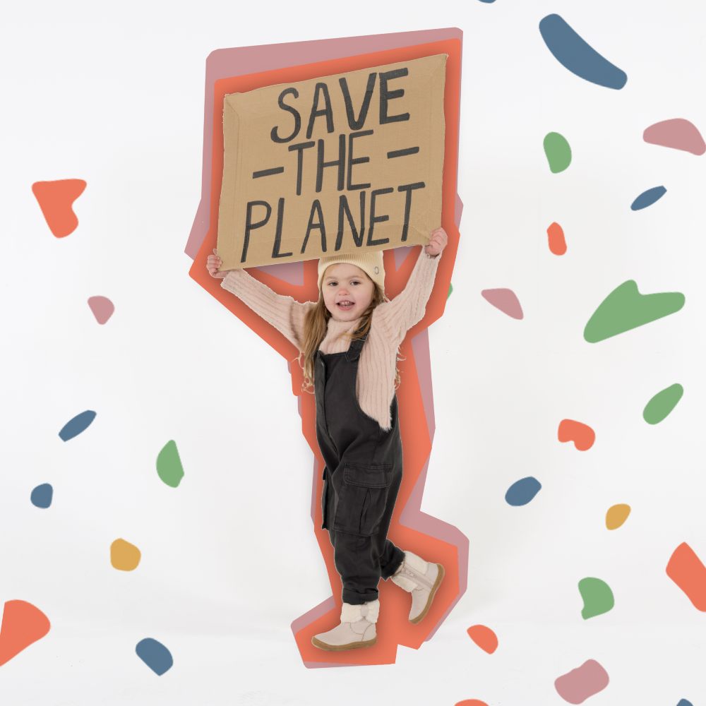 A girl in a pink beanie hat holding up a cardboard banner saying Save the Planet 