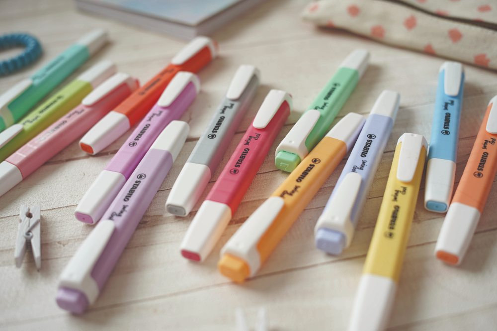 Pastel coloured highlighter pens by Stabilo laid out on a desk