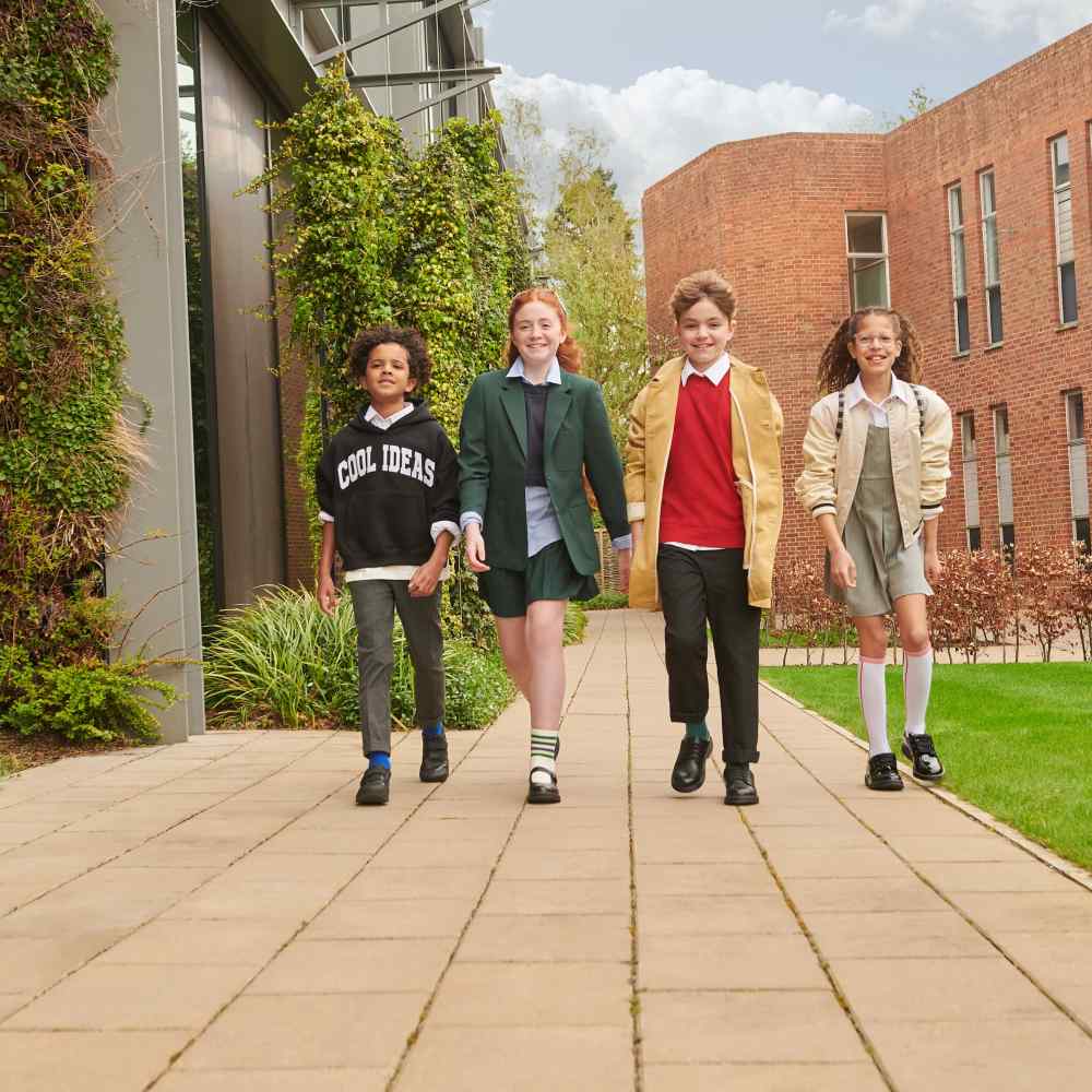 Four children walking side by side outside a school 