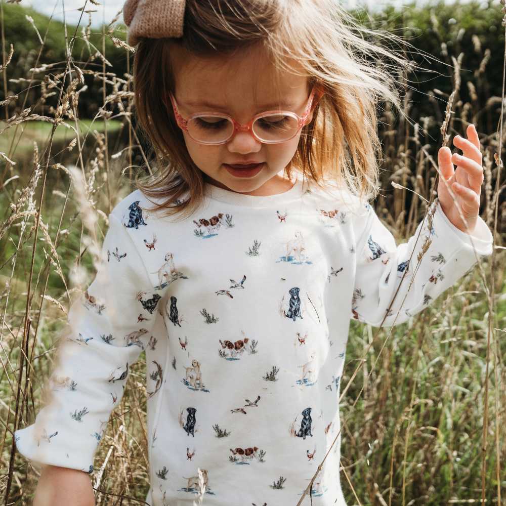 A young girl in glasses stood outside in tall grass