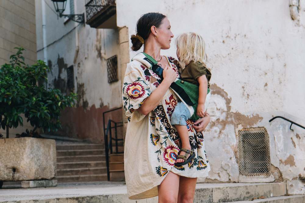 A woman outside carrying a child in a Wildride carrier