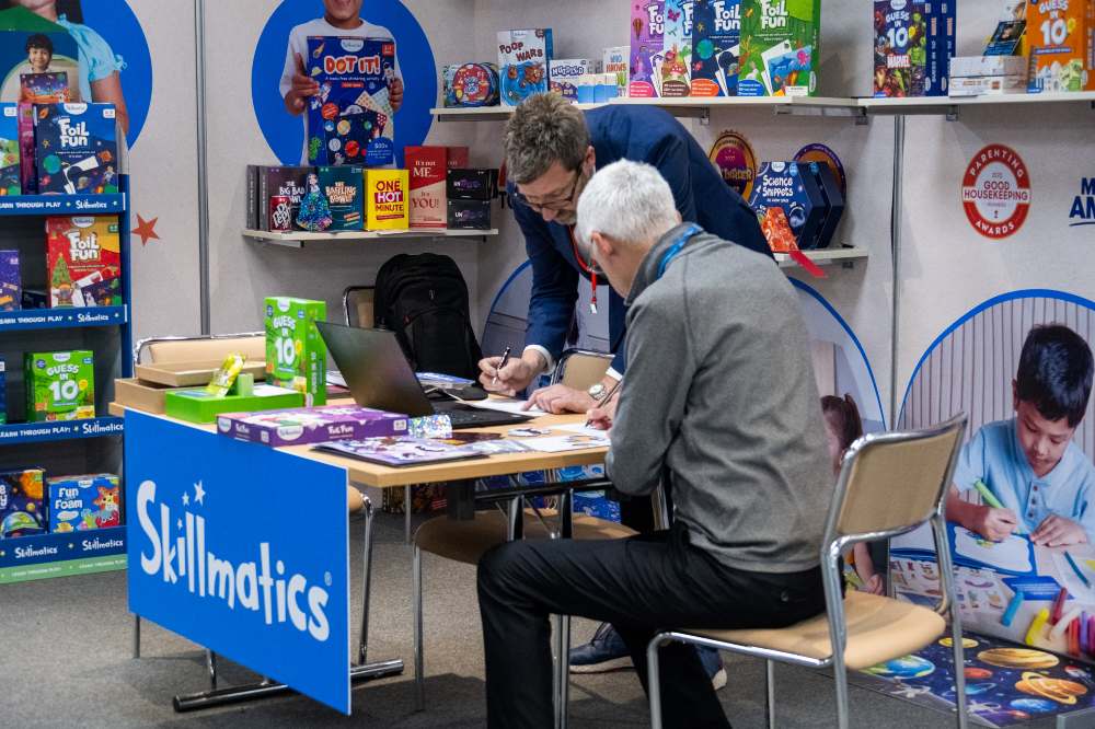 Two men on an exhibition stand displaying toys at the INDX Toys Show 