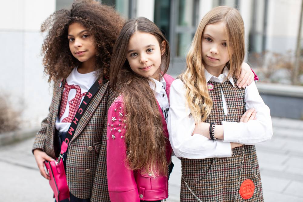 Three girls stood together outside wearing outfits from the John Richmond Kids AW25 collection 