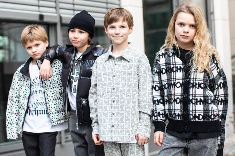 Four boys stood side by side outside wearing black and grey outfits 