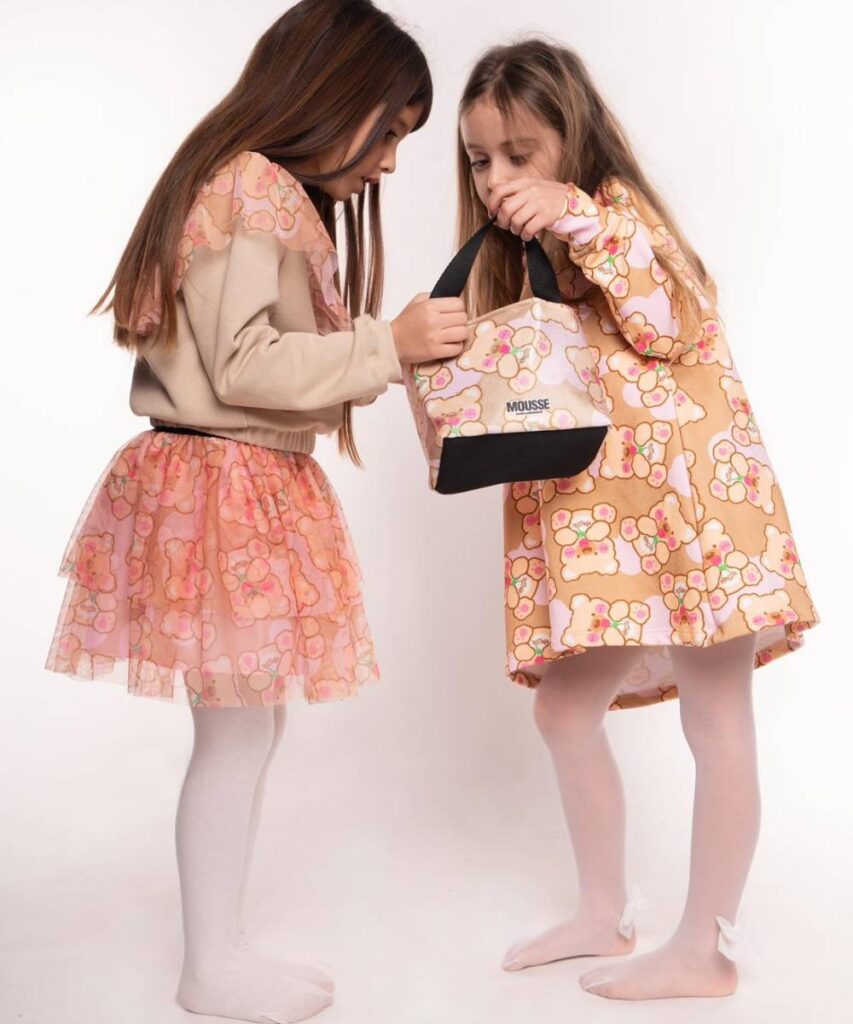 Two girls in bear print outfits looking inside a bear print bag 