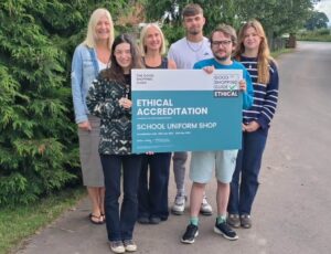 A group of staff from School Uniform Shop stood outside holding up a certificate