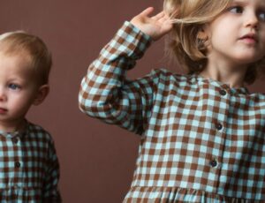 Two children in brown and blue checked outfits against a brown background