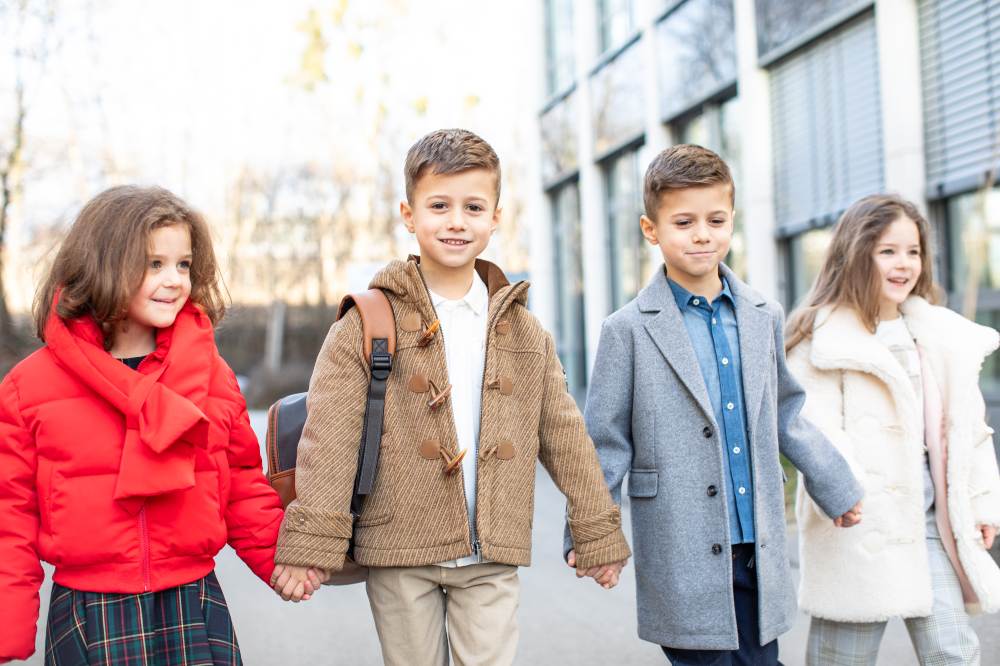 Four children outside a beside a building holding hands 