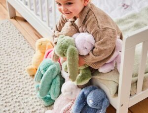 A young girl holding multiple soft toy bunnies in multiple colours