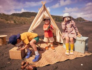 A group of children playing outside on a rug in front of a teepee